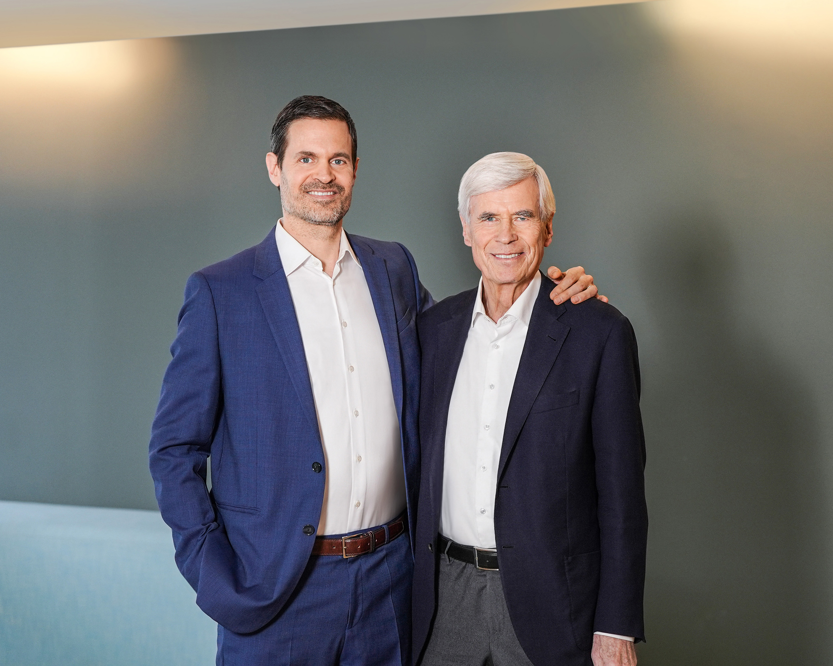 Benjamin und Michael Otto stehen lächelnd in einem modernen Büro mit gelben Wänden.