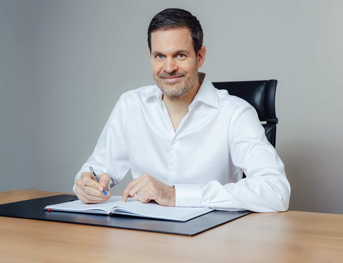 Benjamin Otto sitzt am Schreibtisch mit einem Notizbuch und Stift