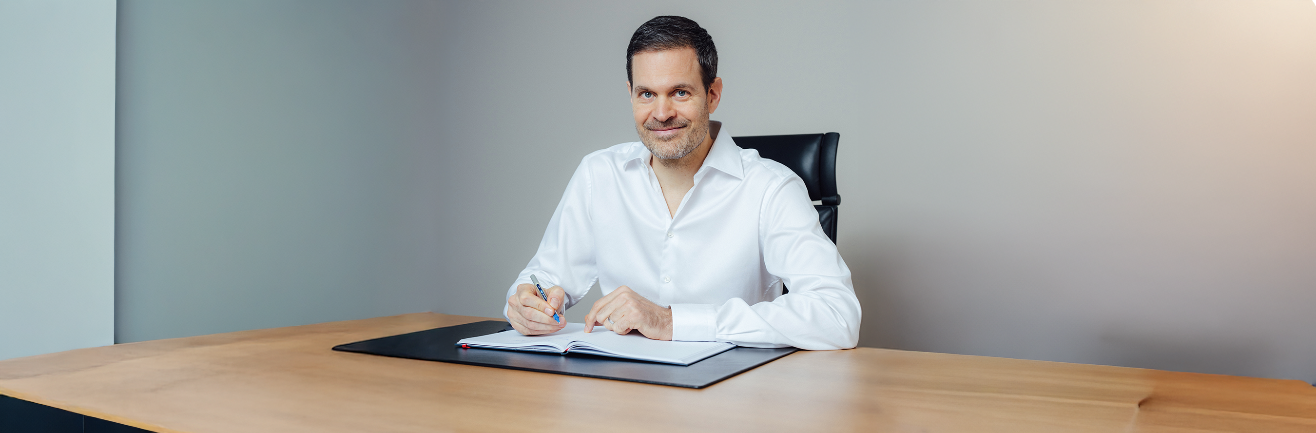 Benjamin Otto sitzt am Schreibtisch mit einem Notizbuch und Stift